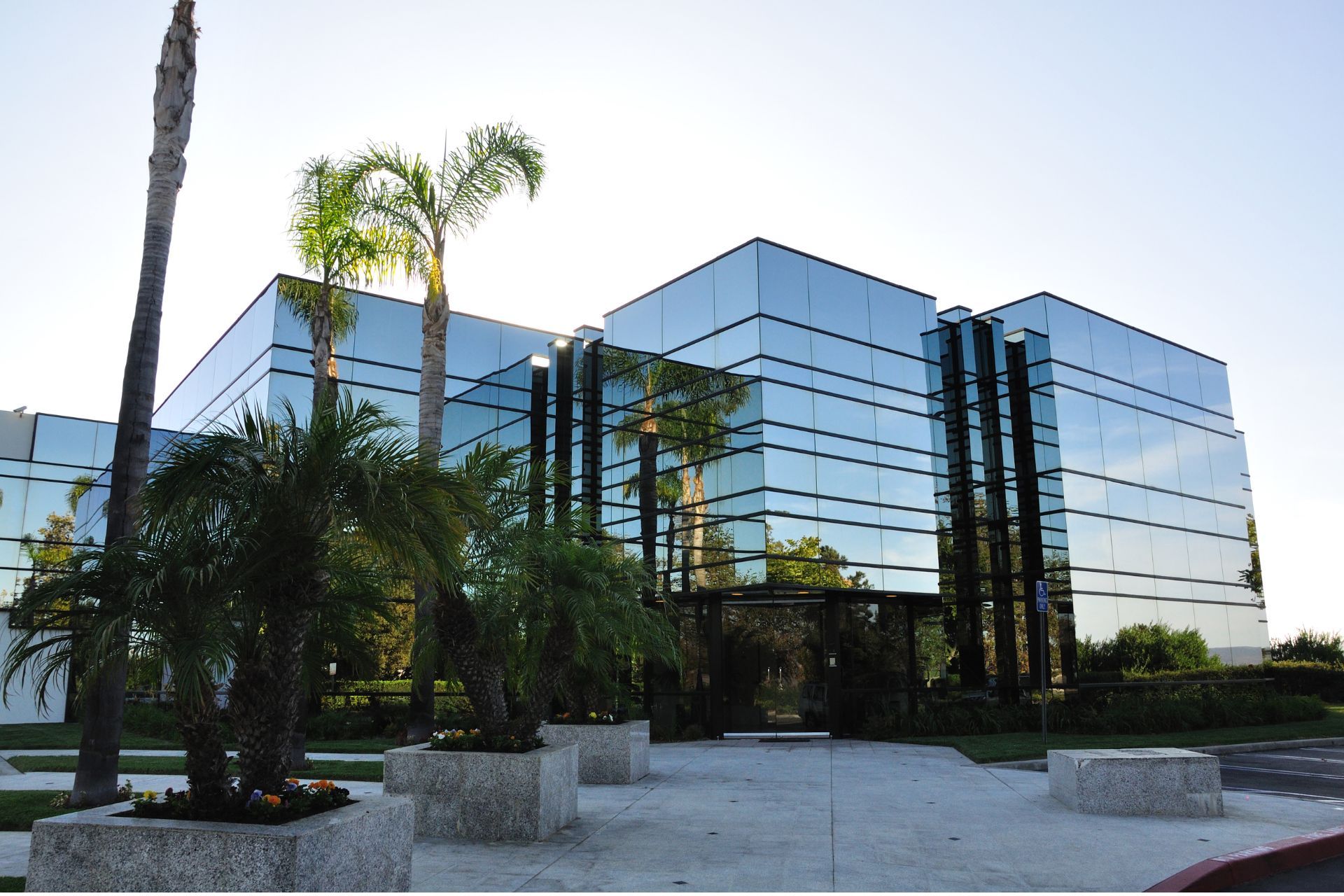 A large glass building with palm trees in front of it