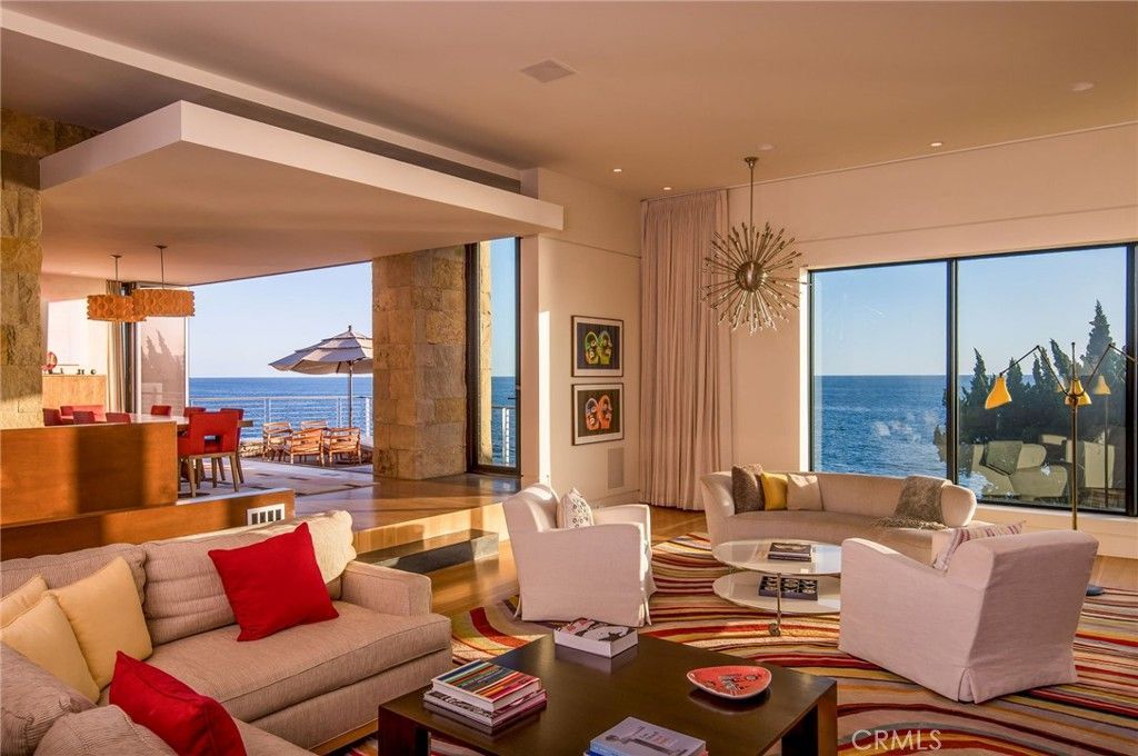 A living room with a couch and chairs and a view of the ocean