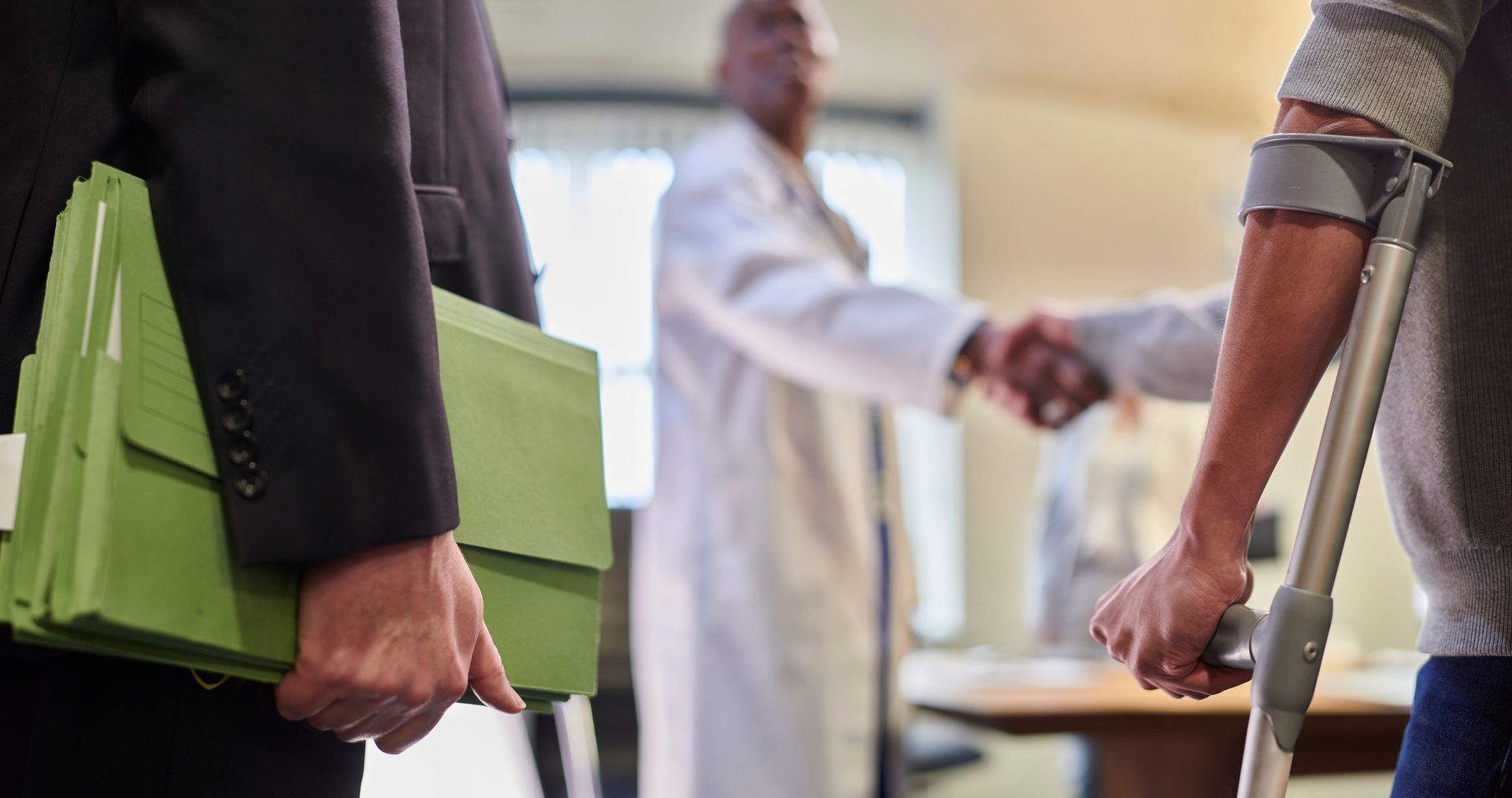 A man with a bandaged hand is sitting at a table talking to a doctor.