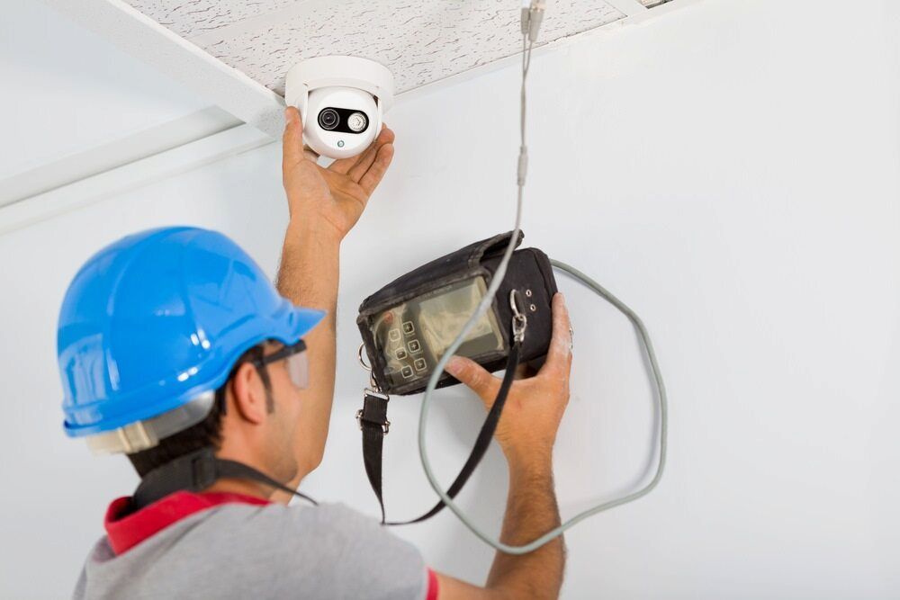 A Man is Installing a Security Camera on the Ceiling — South Coast Locksmiths in Fairy Meadow, NSW