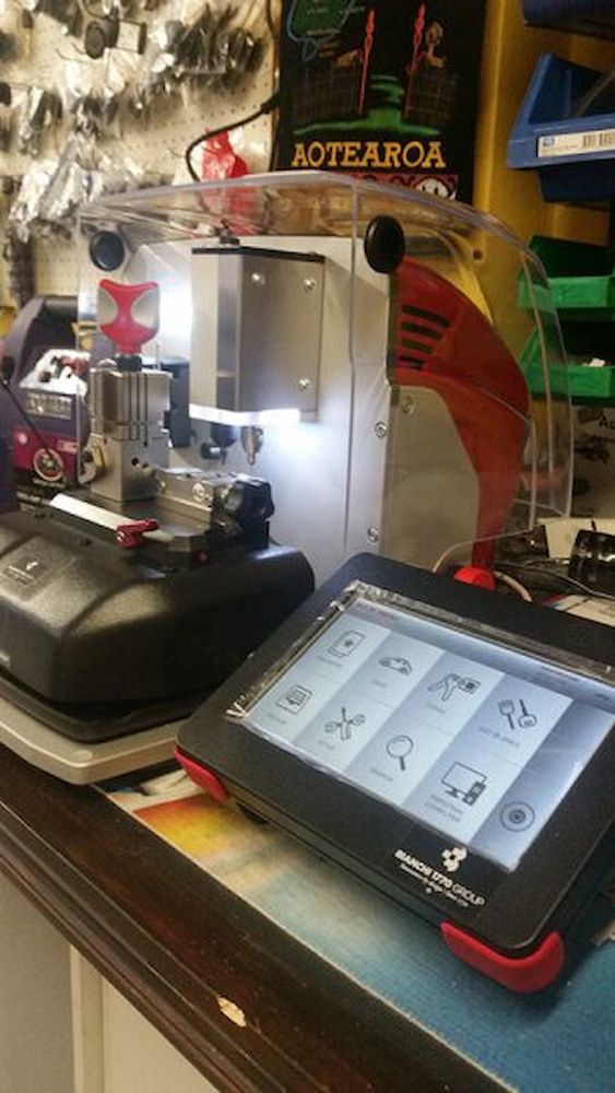 A Key Cutting Machine is Sitting on a Table Next to a Tablet — South Coast Locksmiths in Fairy Meadow, NSW