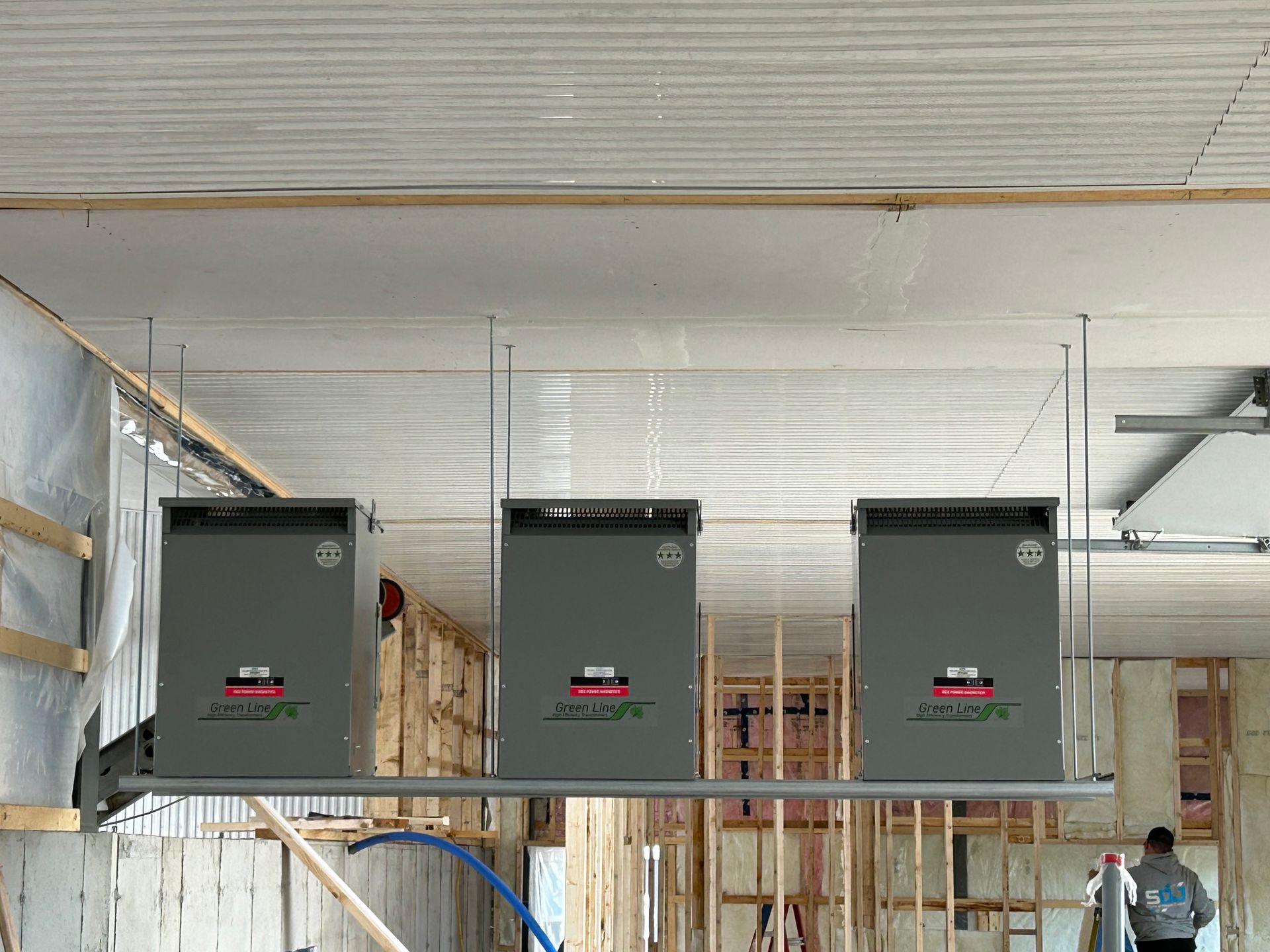 Trois boîtiers électriques sont suspendus au plafond d'un bâtiment en construction.