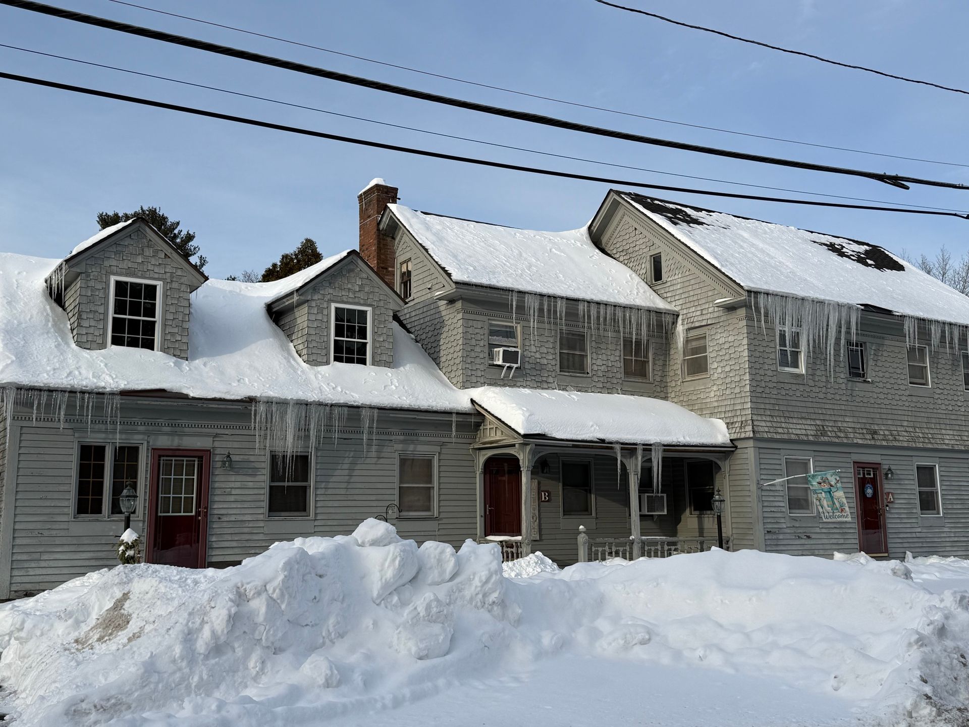 multi-residential building with snow and ice on roof