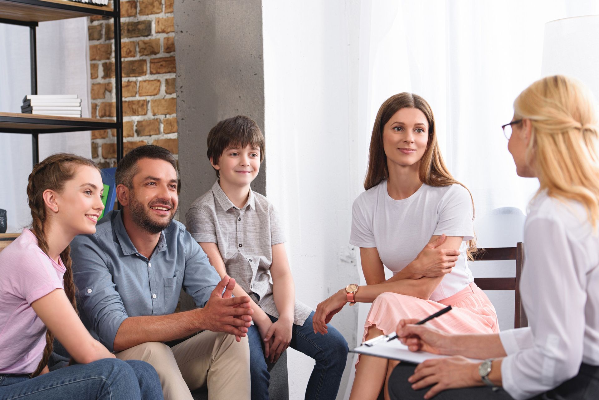 Small group in a counseling session, seated and talking with a therapist in a bright room. Small group in a counseling session, seated and talking with a therapist in a bright room.