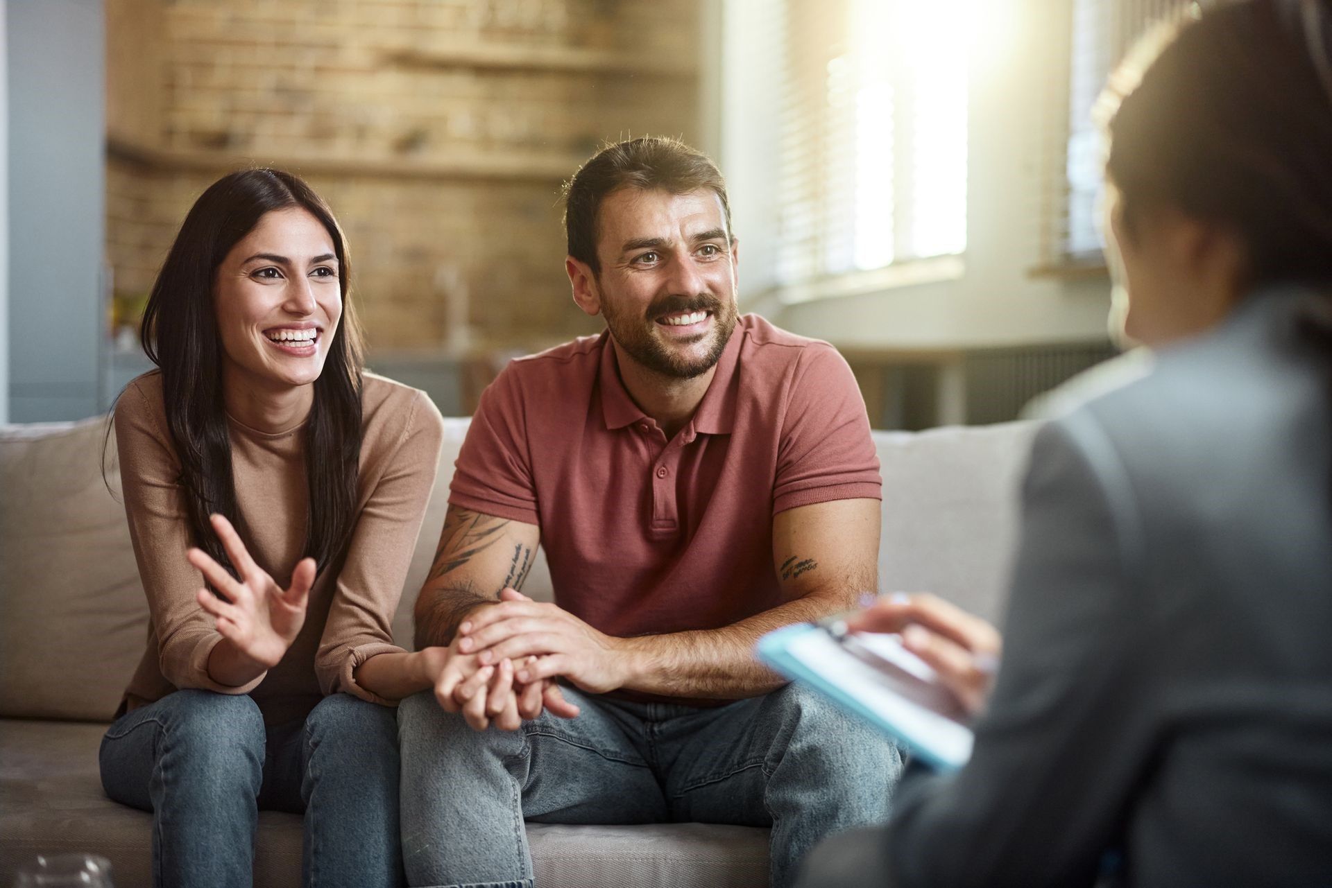 Smiling couple talking with a counselor in a bright living room during a session