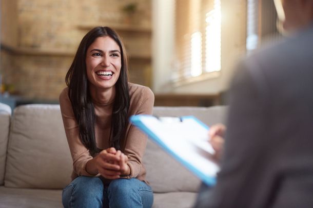 Smiling woman in a living room, speaking with a person holding a clipboard. Smiling woman in a living room, speaking with a person holding a clipboard.