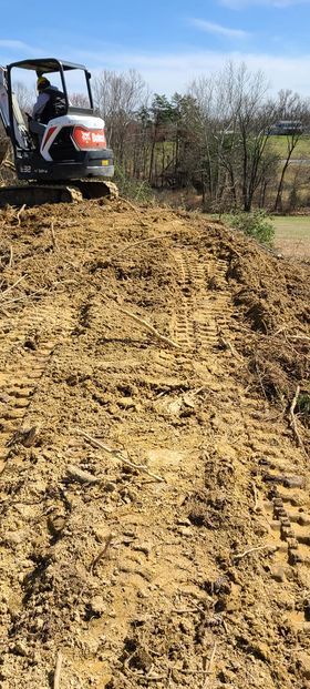 Man driving a bulldozer on top of a pile of dirt and branch - Campbellsburg, IN | Twisted Electric LLC 