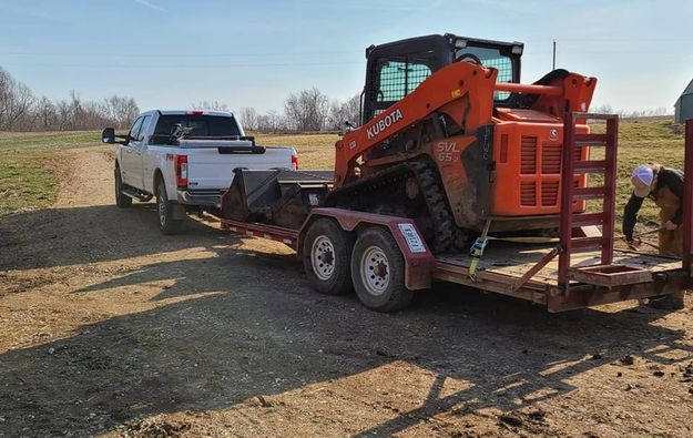 White truck towing a small orange bulldozer on a trailer - Campbellsburg, IN | Twisted Electric LLC 