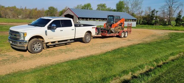 White truck towing a trailer with an orange tractor on it - Campbellsburg, IN | Twisted Electric LLC 