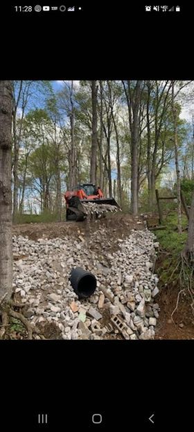 Bulldozer sitting on top of a pile of large rocks in the woods with black pipe - Campbellsburg, IN | Twisted Electric LLC 
