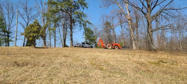 Orange tractor parked in the middle of a field next to a truck - Campbellsburg, IN | Twisted Electric LLC 