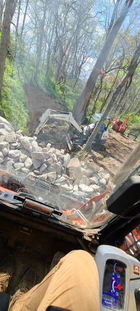 Worker sitting in the driver's seat of a bulldozer with huge rocks - Campbellsburg, IN | Twisted Electric LLC 