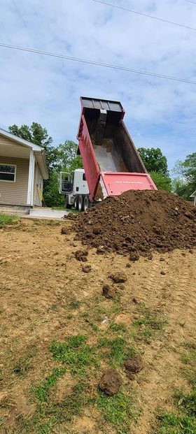 Red dump truck dumping a large pile of dirt in front of a house - Campbellsburg, IN | Twisted Electric LLC 