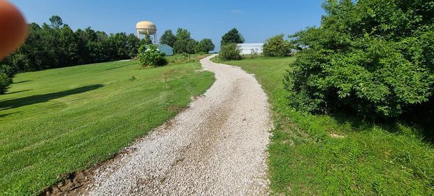 Gravel road going through a grassy field with a water tower - Campbellsburg, IN | Twisted Electric LLC 