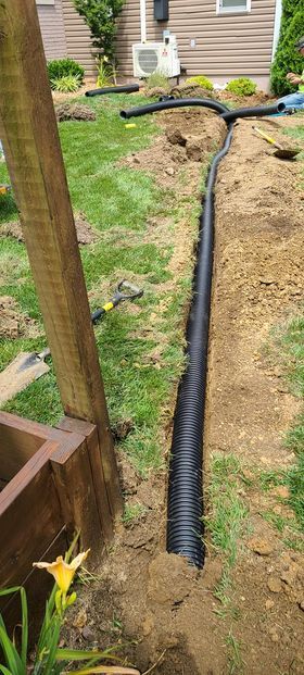 Black drain pipe installation in a yard next to a wooden post - Campbellsburg, IN | Twisted Electric LLC 