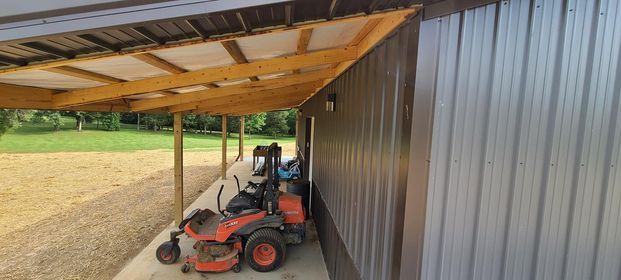 Lawn mower parked under a covered porch next to a building - Campbellsburg, IN | Twisted Electric LLC 