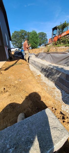 Man standing in the dirt next to a retaining wall - Campbellsburg, IN | Twisted Electric LLC 