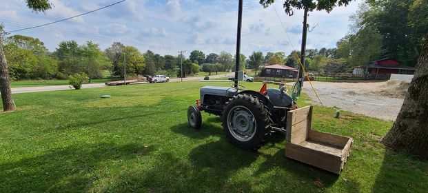 Old tractor is parked in a grassy field next to a wooden box - Campbellsburg, IN | Twisted Electric LLC 