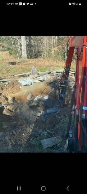 Red excavator digging a hole in the ground with junk - Campbellsburg, IN | Twisted Electric LLC 