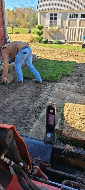 Man laying a lawn in a backyard next to a tractor - Campbellsburg, IN | Twisted Electric LLC 
