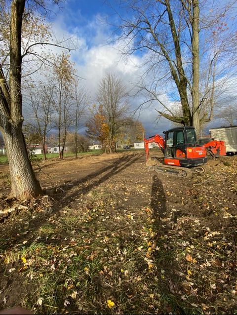 Red excavator sitting in the middle of a field surrounded by leafless tree - Campbellsburg, IN | Twisted Electric LLC 