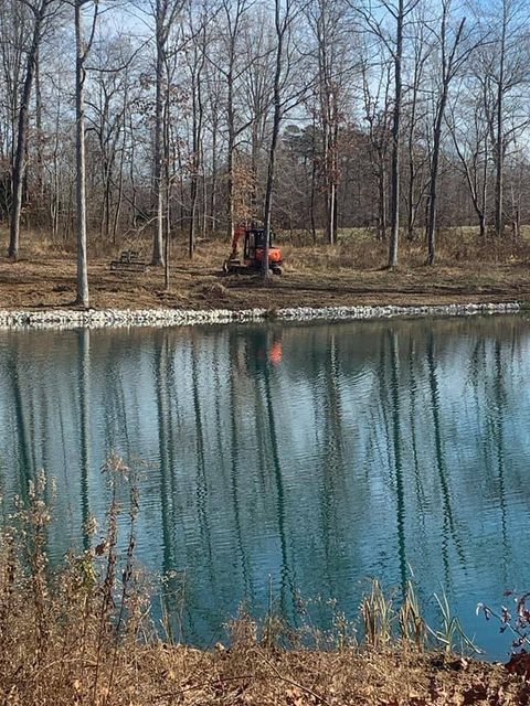 Excavator working on the shore of a lake surrounded by trees - Campbellsburg, IN | Twisted Electric LLC 