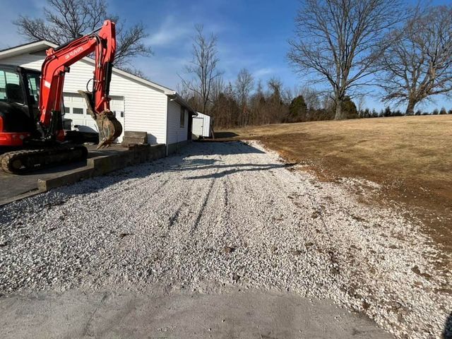 Red excavator digging a gravel driveway in front of a white house - Campbellsburg, IN | Twisted Electric LLC 