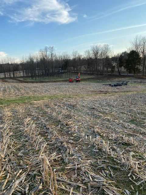 Field of dry grass with a tractor in the background - Campbellsburg, IN | Twisted Electric LLC 