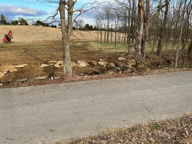 Red excavator working on a dirt field next to trees without leaves - Campbellsburg, IN | Twisted Electric LLC 
