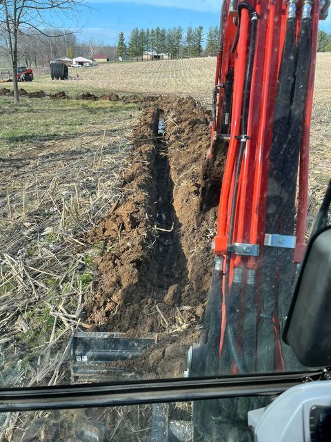 Red excavator digging a trench in a field with red excavator in the background - Campbellsburg, IN | Twisted Electric LLC 