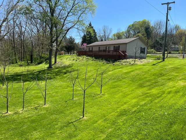 House with a red deck sitting on top of a lush green hill with baby trees - Campbellsburg, IN | Twisted Electric LLC 