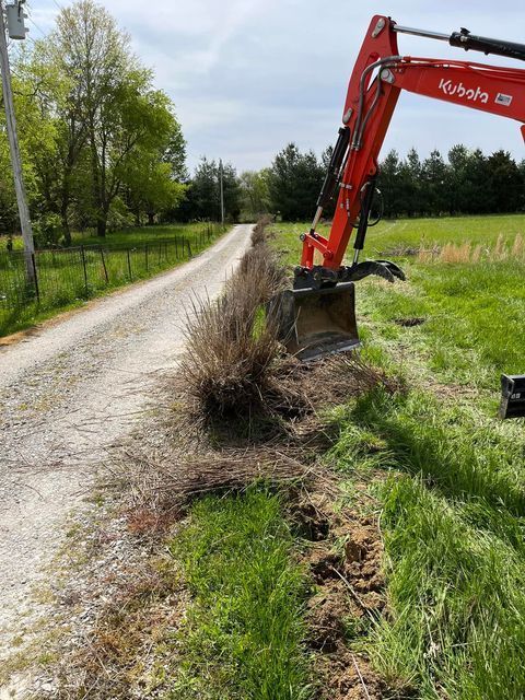 Red excavator digging next to a dirt road with forest background and fence - Campbellsburg, IN | Twisted Electric LLC 