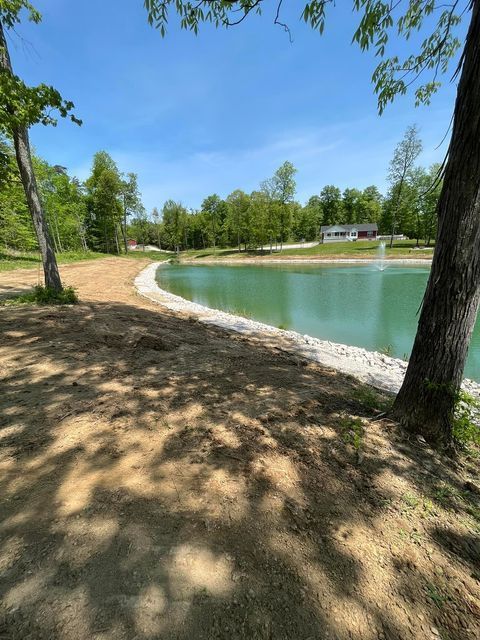 Large pond surrounded by trees and dirt with a house in the background - Campbellsburg, IN | Twisted Electric LLC 