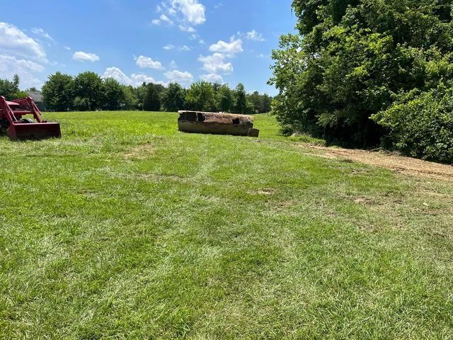 Red tractor parked in the middle of a grassy field - Campbellsburg, IN | Twisted Electric LLC 