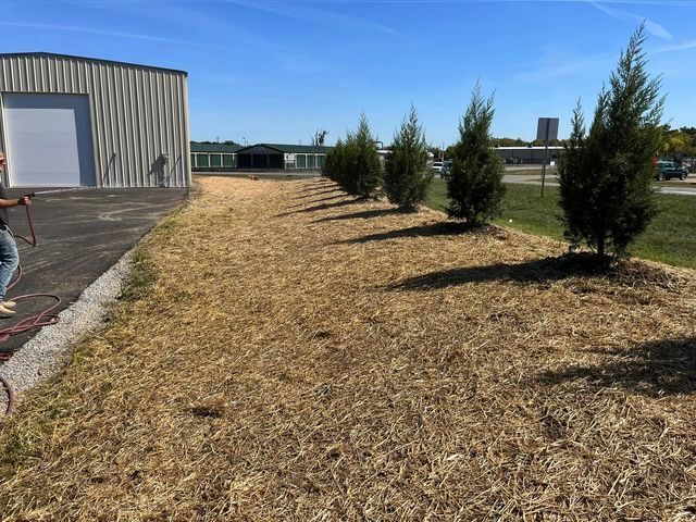 Man spraying a lawn with a hose in front of a building - Campbellsburg, IN | Twisted Electric LLC 