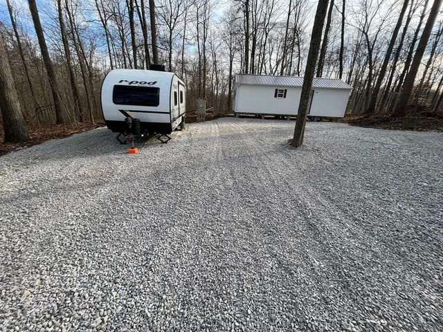 White RV parked in a gravel lot in the woods - Campbellsburg, IN | Twisted Electric LLC 