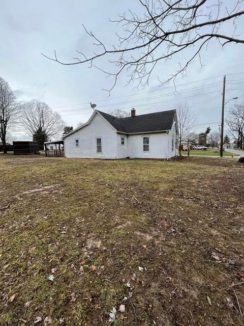 White house with a black roof sitting in the middle of a grassy field - Campbellsburg, IN | Twisted Electric LLC .