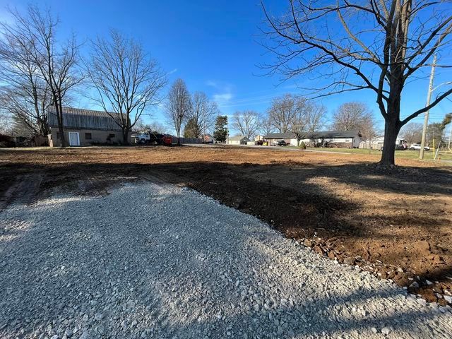 Dirt lot with a house in the background and trees in the foreground - Campbellsburg, IN | Twisted Electric LLC 