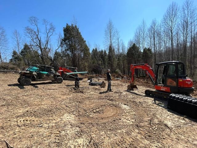 Man standing in a dirt field next to a bulldozer on a clear sky - Campbellsburg, IN | Twisted Electric LLC 