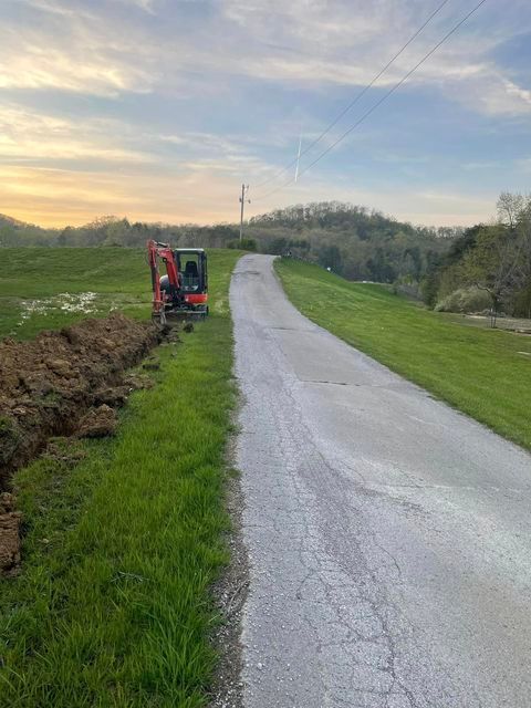 Small excavator sitting on the side of a road next to a grassy field - Campbellsburg, IN | Twisted Electric LLC 