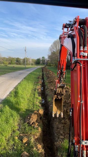 Red excavator digging a trench next to a road - Campbellsburg, IN | Twisted Electric LLC 