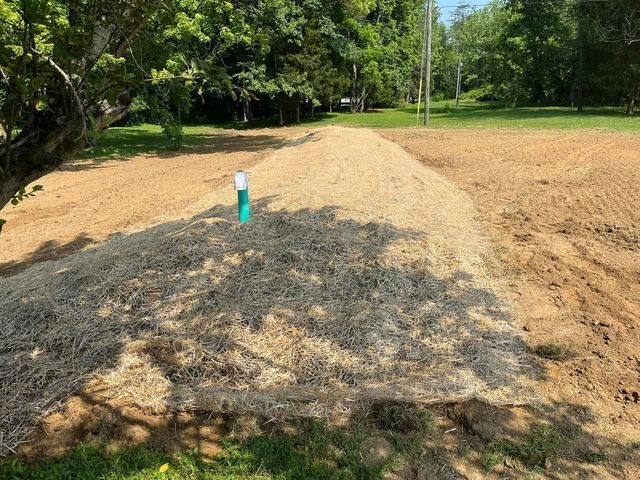 Pile of hay sitting in the middle of a dirt field next to a tree - Campbellsburg, IN | Twisted Electric LLC 