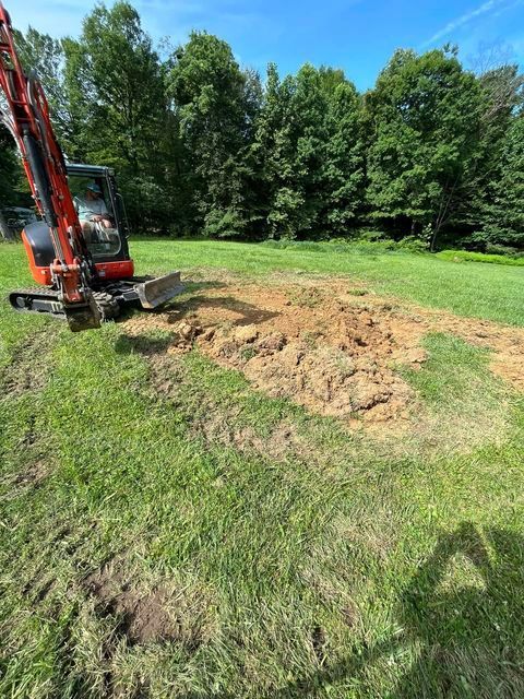 Red excavator digging a hole in the middle of a grassy field - Campbellsburg, IN | Twisted Electric LLC 