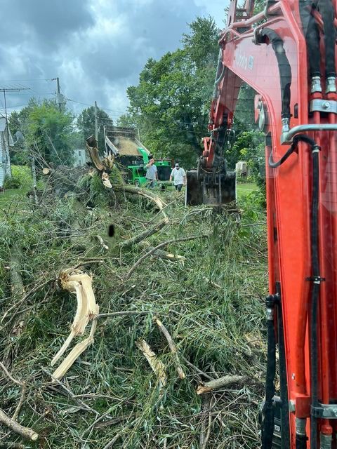 Red excavator digging through a pile of branches - Campbellsburg, IN | Twisted Electric LLC 