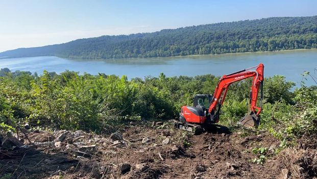 Red excavator is working on a hill next to a river - Campbellsburg, IN | Twisted Electric LLC 