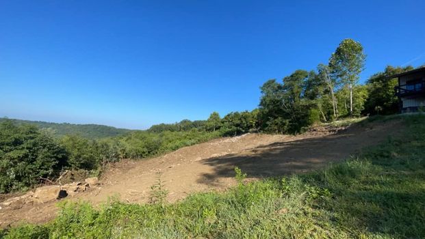 Large dirt field with trees and a house in the background - Campbellsburg, IN | Twisted Electric LLC 