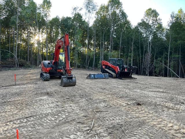 Red excavator and a red tractor parked in a dirt field - Campbellsburg, IN | Twisted Electric LLC 