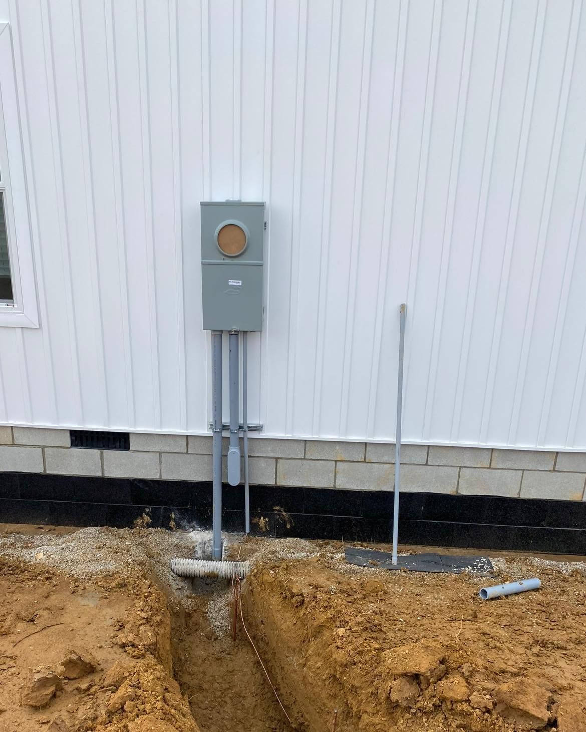 A electrical box is being installed on the side of a house.