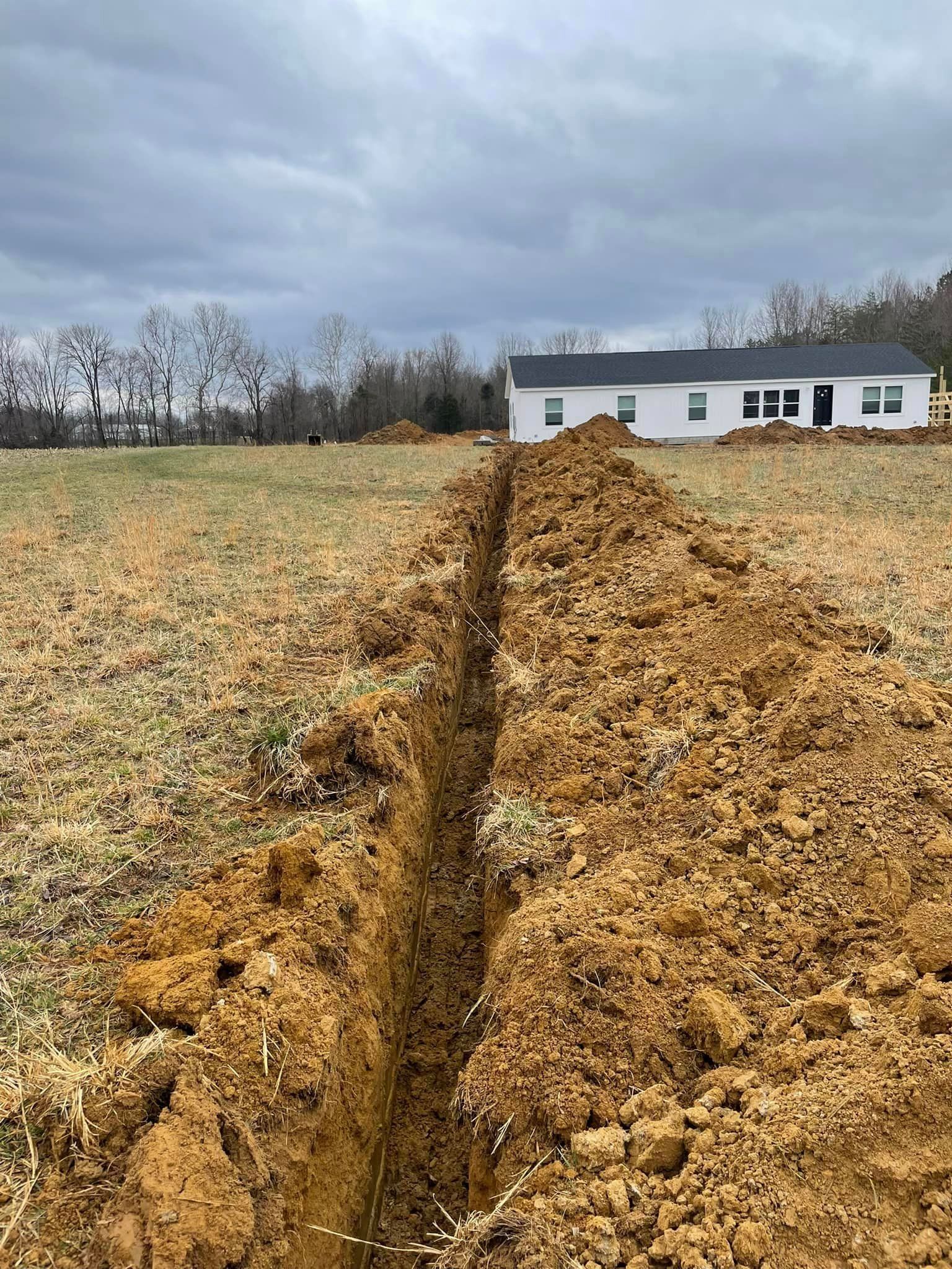 A large pile of dirt in a field with a house in the background.