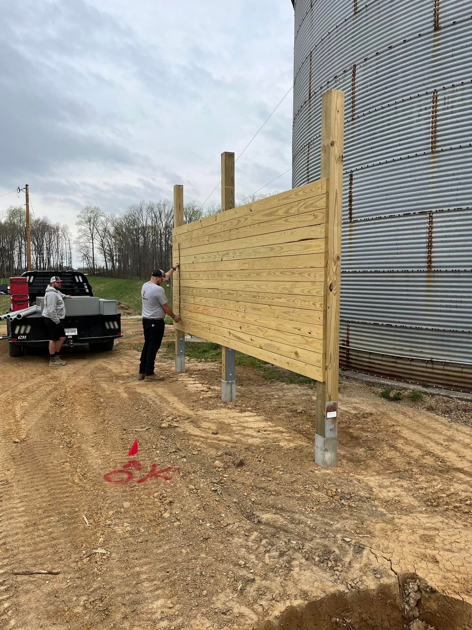 A group of people are working on a wooden fence in front of a building | Campbellsburg, IN | Twisted Electric LLC